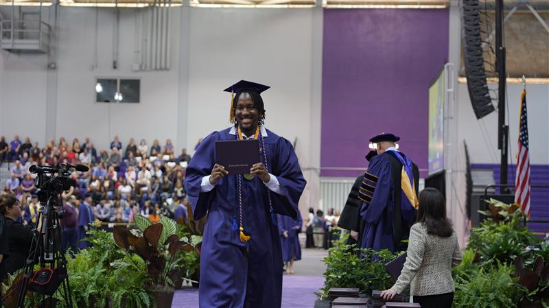 Student walking off the commencement stage after receiving diploma